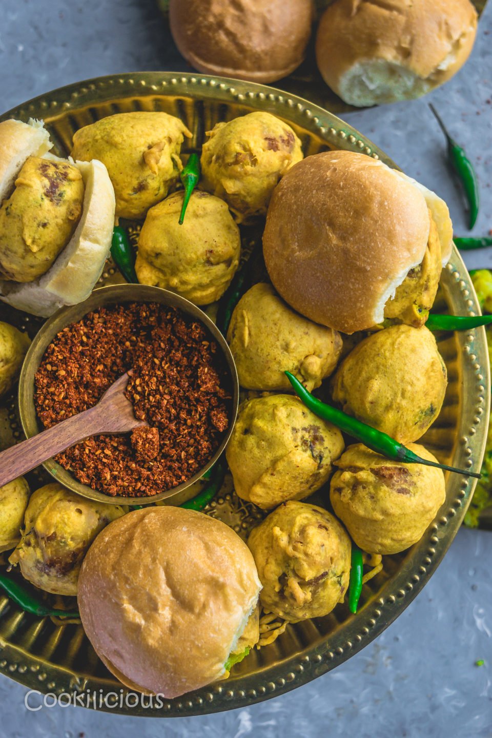 a plate full of vada pav with a bowl of garlic masala in the middle