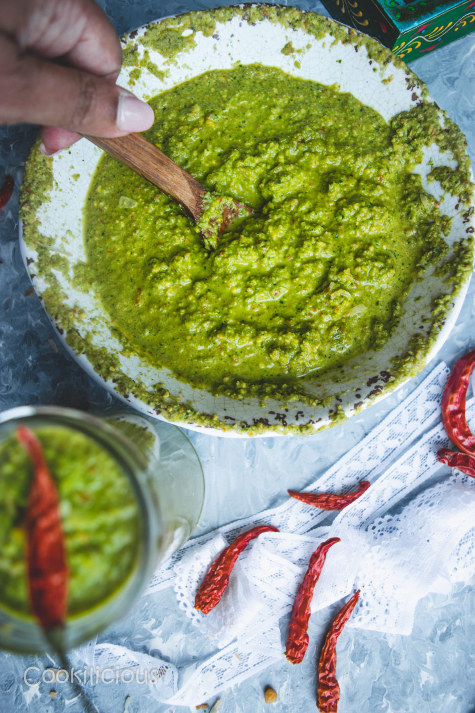 a hand dipping a wooden spoon into a bowl of Indian Green Chutney with Leftover Lettuce Leaves