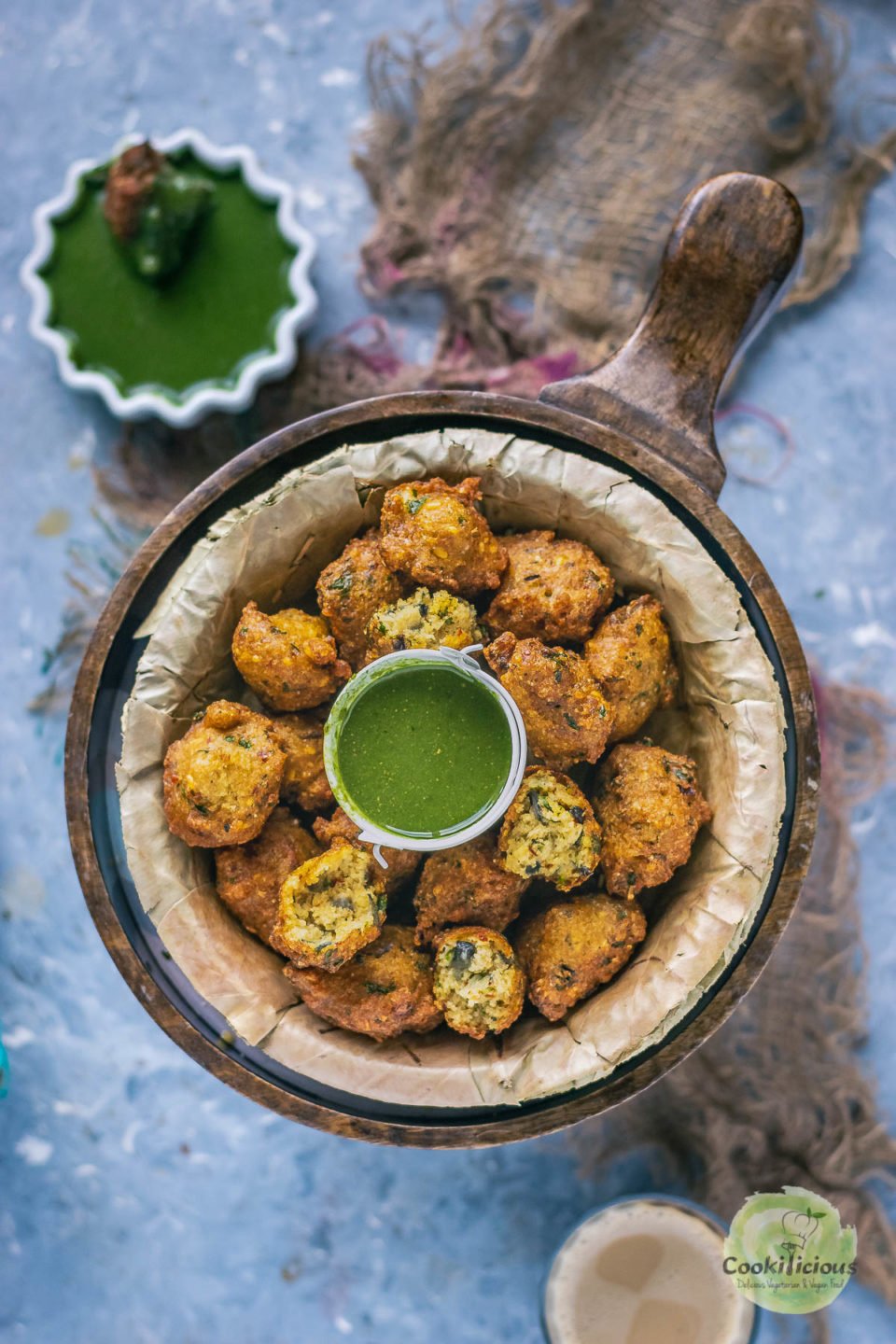 Crispy Moong Dal Pakora which is one of the easy vegan appetizers is placed in a round platter with a bowl of chutney in the middle and next to it