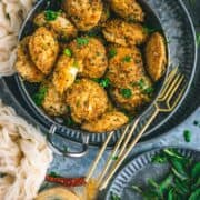 top angle view of Mini Masala Idli in a small kadai with a tray full of curry leaves on the side