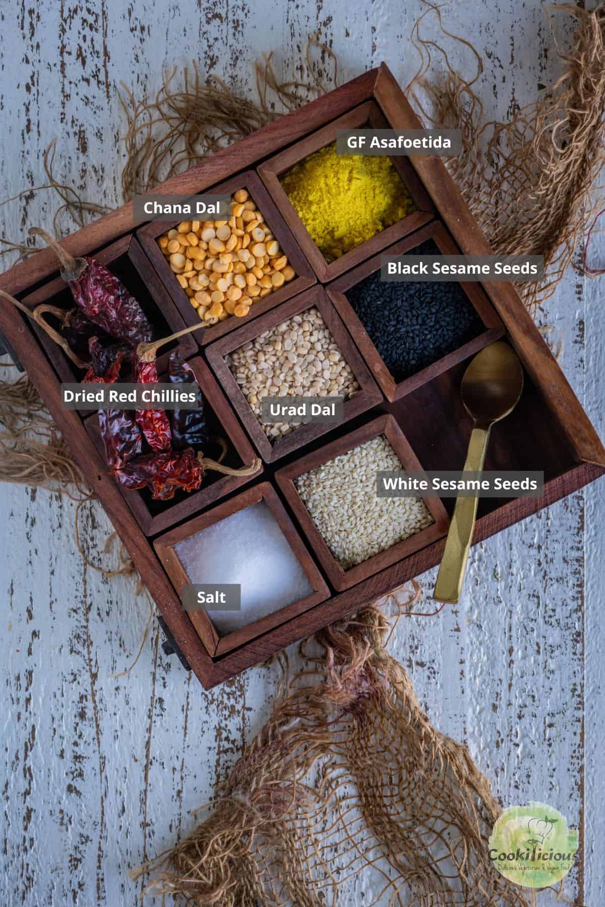 All ingredients needed to make Idli Podi placed in a spice box with labels on them.