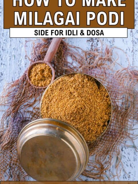 Dosa molaga podi served in a small brass dabba with a lid and spoon on the side and text at the top and bottom.