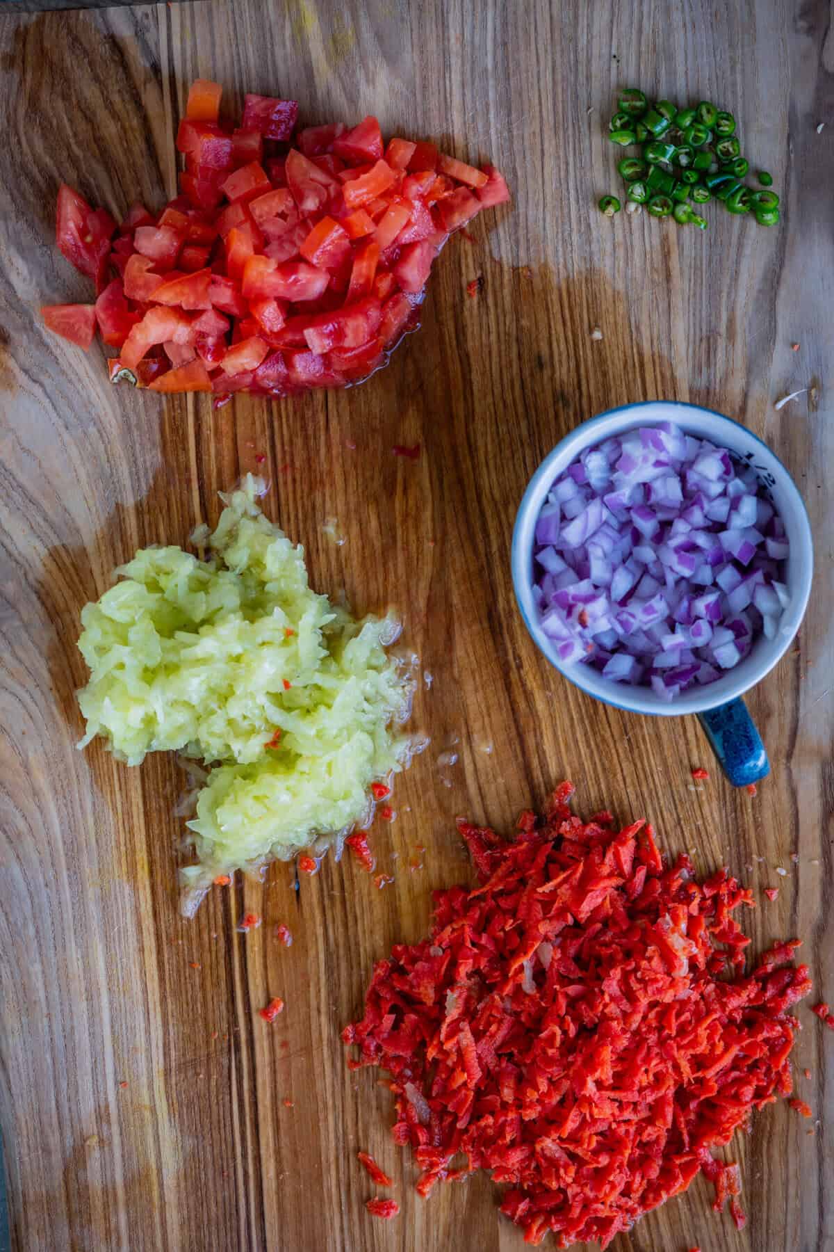 Finely chopped onions and tomatoes with grated carrot and cucumber for koshimbir recipe.