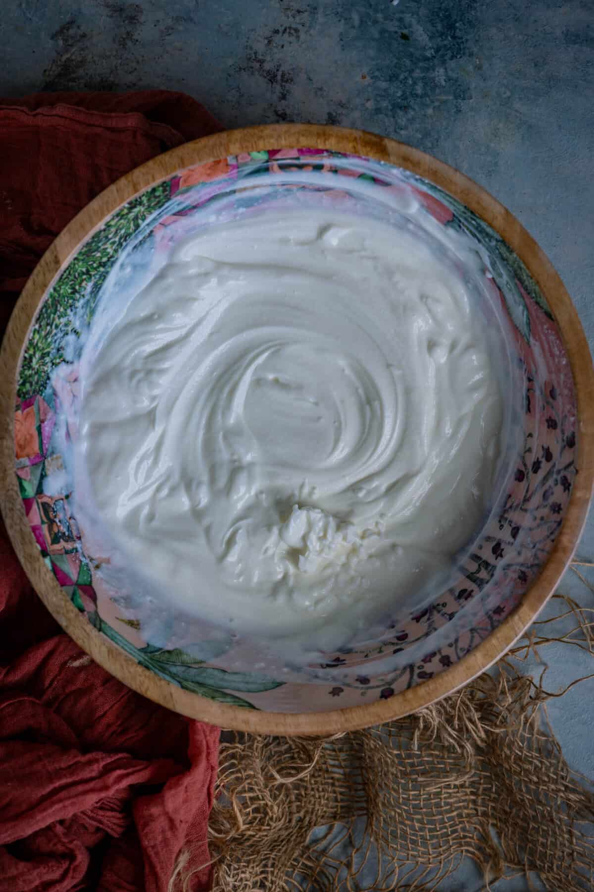 Smooth whisked yogurt base for koshimbir being thinned with water.