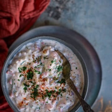 Close-up of koshimbir garnished with cilantro and red chili powder in a bowl with a spoon.