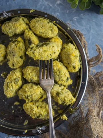 a side shot of a plate filled with Spicy Steamed Lentil Balls and a fork over it