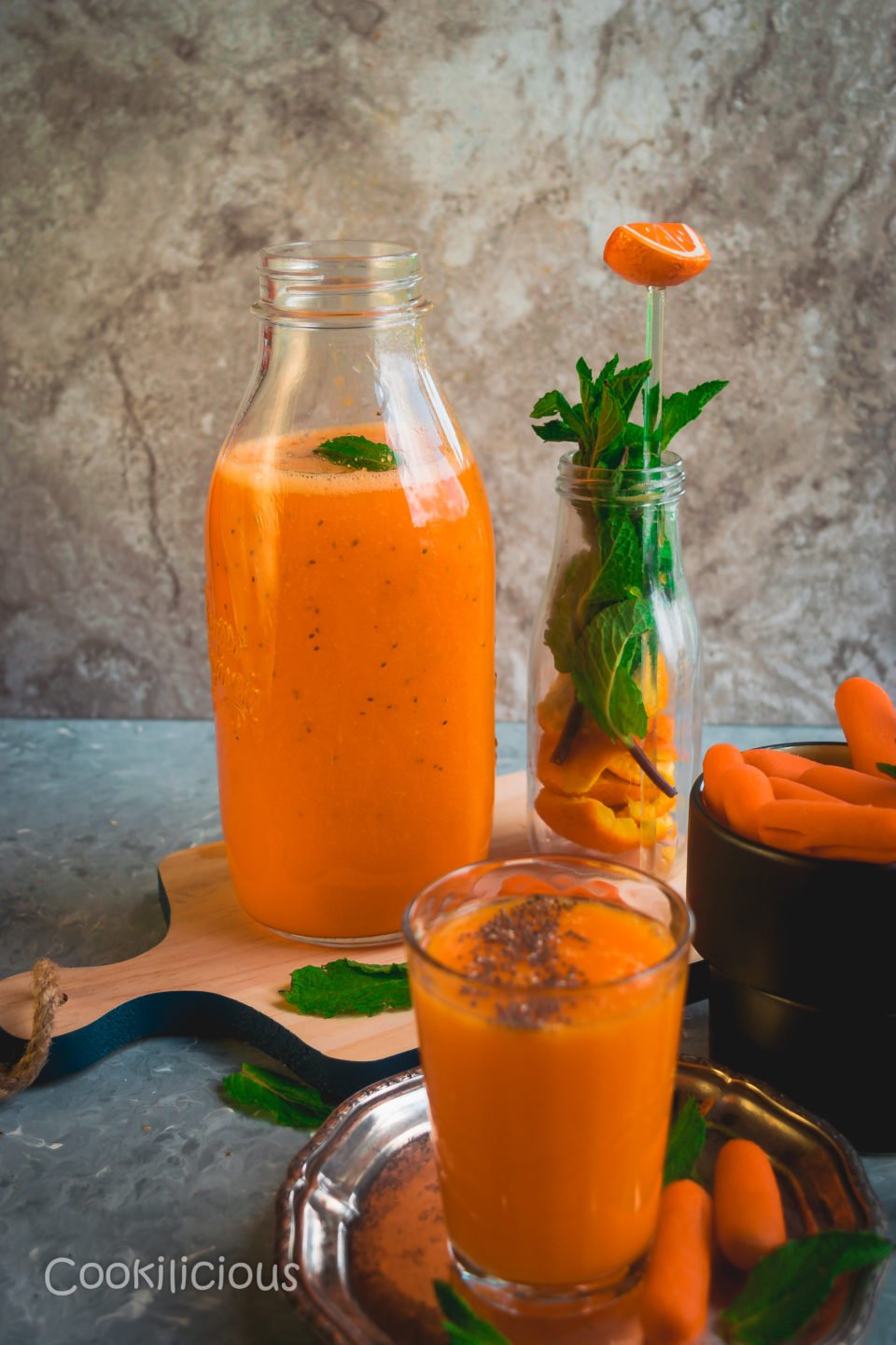 a table set up where a bottle filled with Immune Boosting Sunshine Smoothie in placed behind a glass of the same juice