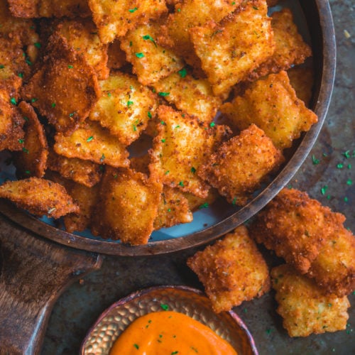 Copycat Olive Garden Cheesy Fried Ravioli in a tray with a dip on the side