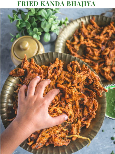 a child's hand reaching out to a plate filled with Vegan Crispy Onion Pakoda | Fried Kanda Bhajiya and text on top