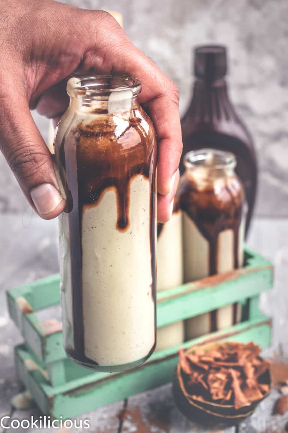 a hand picking up a bottle filled with Chocolate Avocado Smoothie