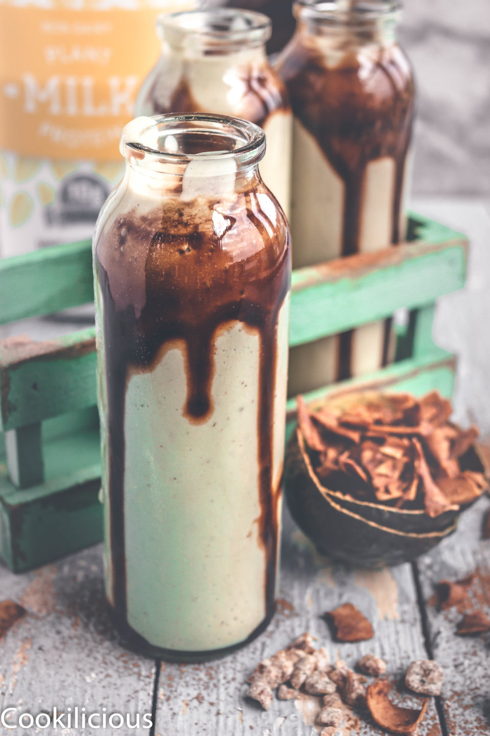 front angle shot of a bottle filled with Chocolate Avocado Smoothie with coconut chips on the side