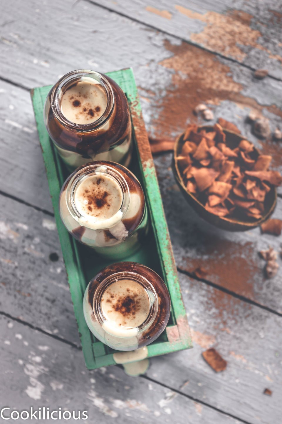 top angle shot of 3 bottles filled with Chocolate Avocado Smoothie and a side of coconut chips