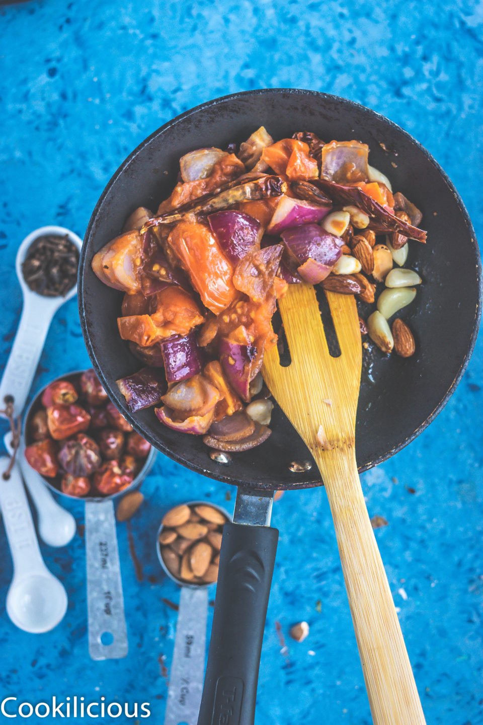 All ingredients used to make South Indian Tomato Almond Chutney in a pan with a spatula in it