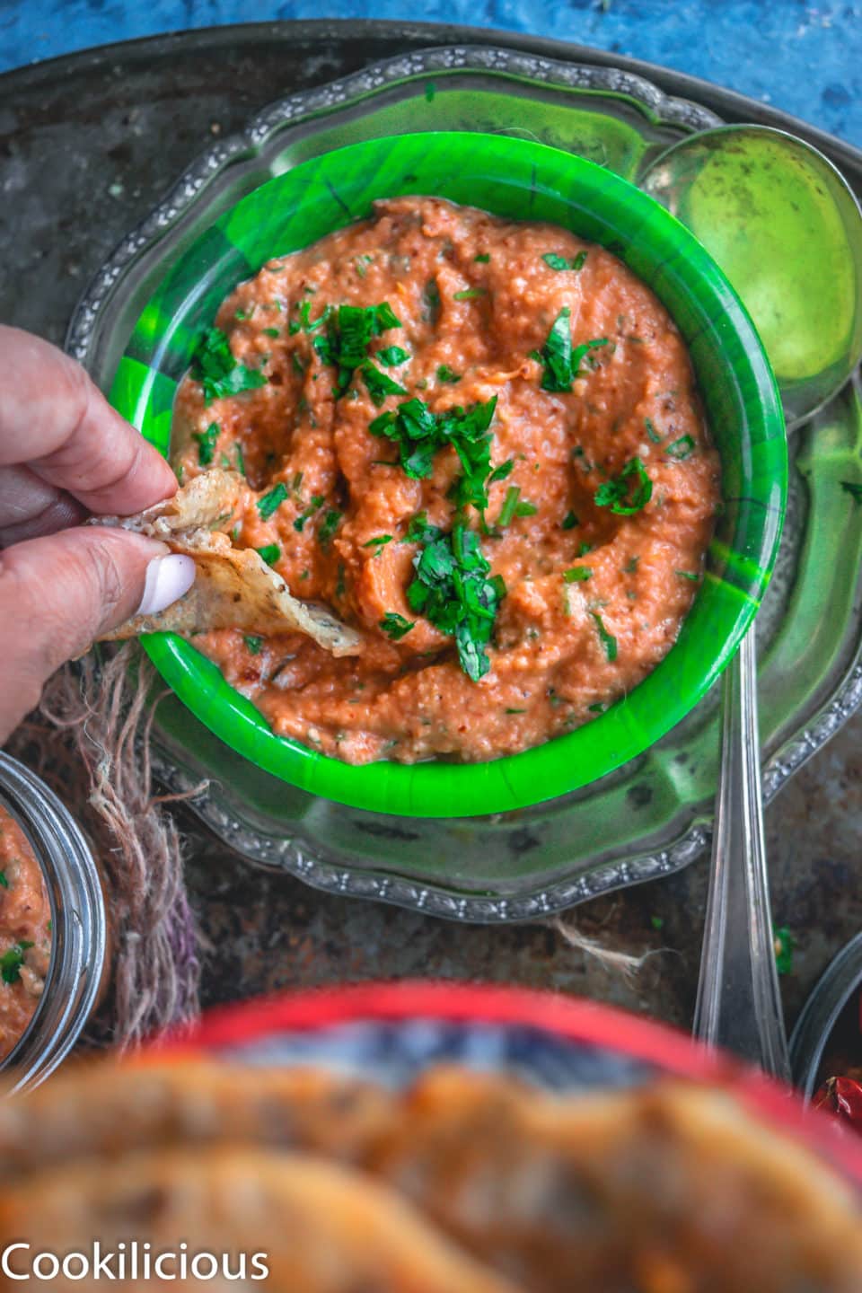 a hand digging a piece of dosa into a bowl of South Indian Tomato Almond Chutney