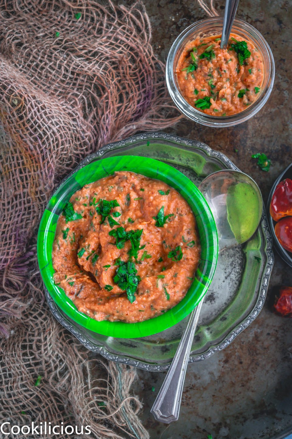 top angle shot of a bowl of South Indian Tomato Almond Chutney with a spoon besides it