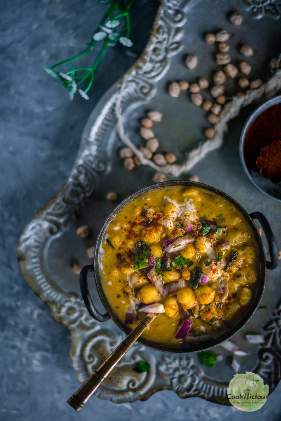 Instant Pot Potato Chickpeas Vegan Curry served in a bowl with a spoon in it placed over a tray