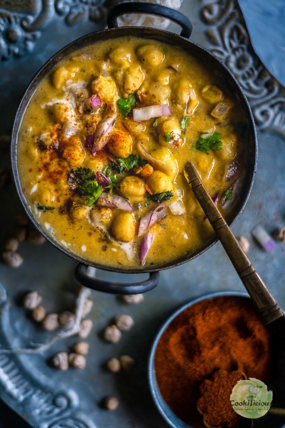 a small bowl filled with Instant Pot Potato Chickpeas Vegan Curry with a spoon in it