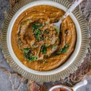 a bowl of tomato onion chutney with a tempering of mustard seeds and cilantro on top.