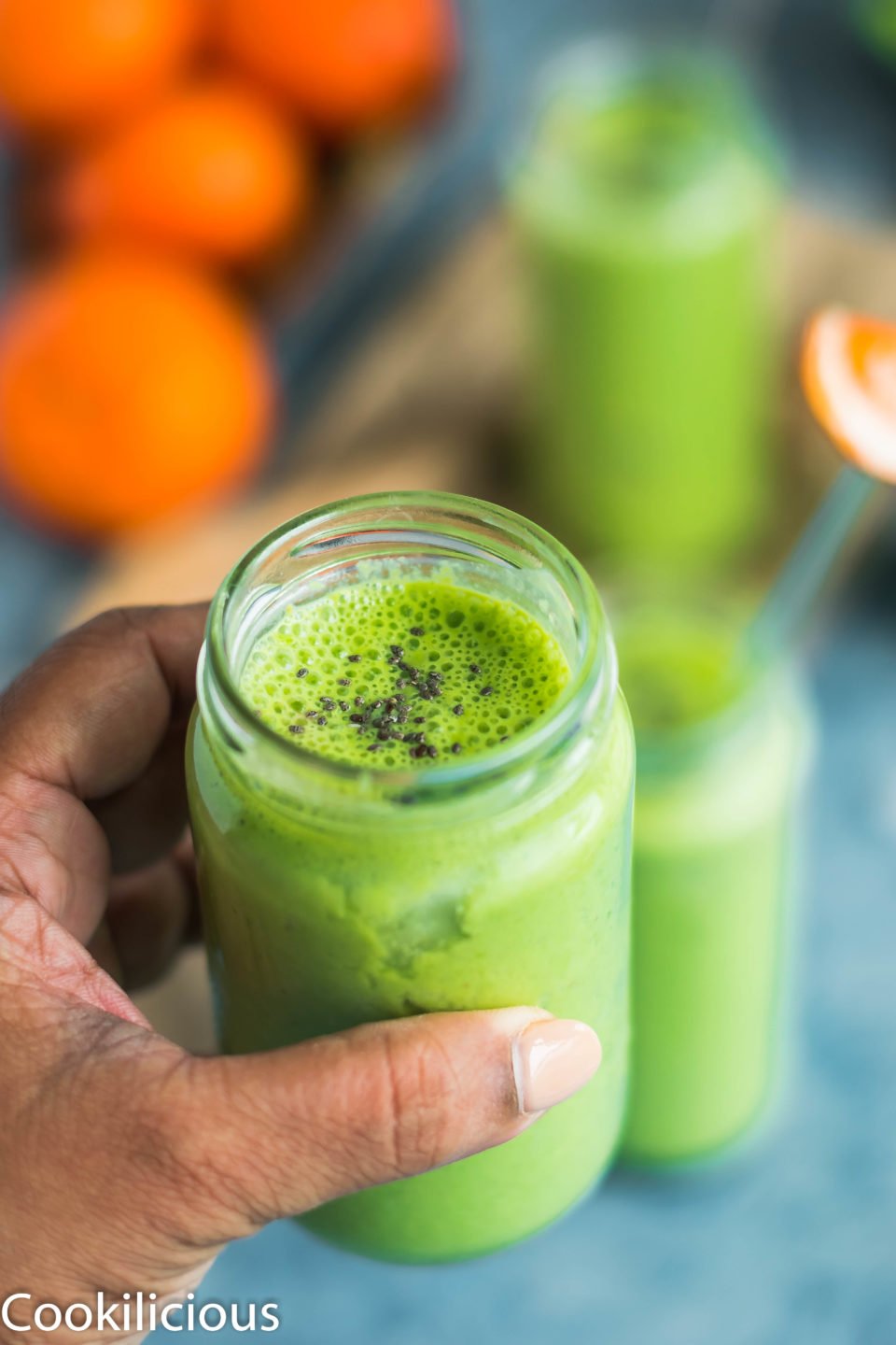 a hand holding a glass of Super Healthy Mango Spinach Yogurt Power Smoothie