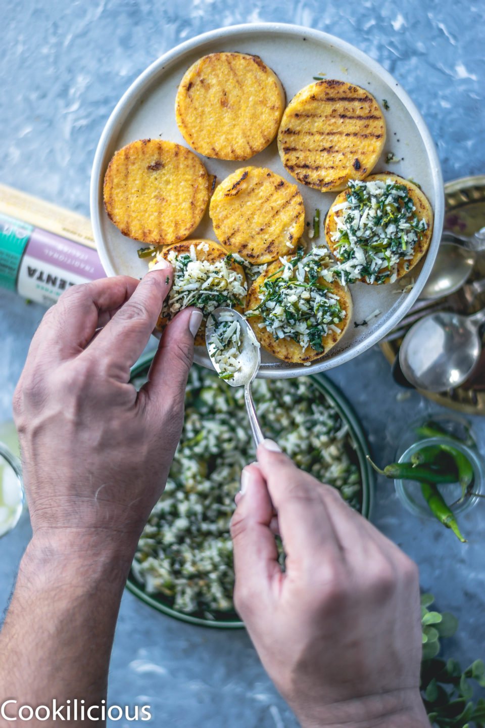 a set of hands spreading the masala over the grilled polenta (vegan gluten free recipes)