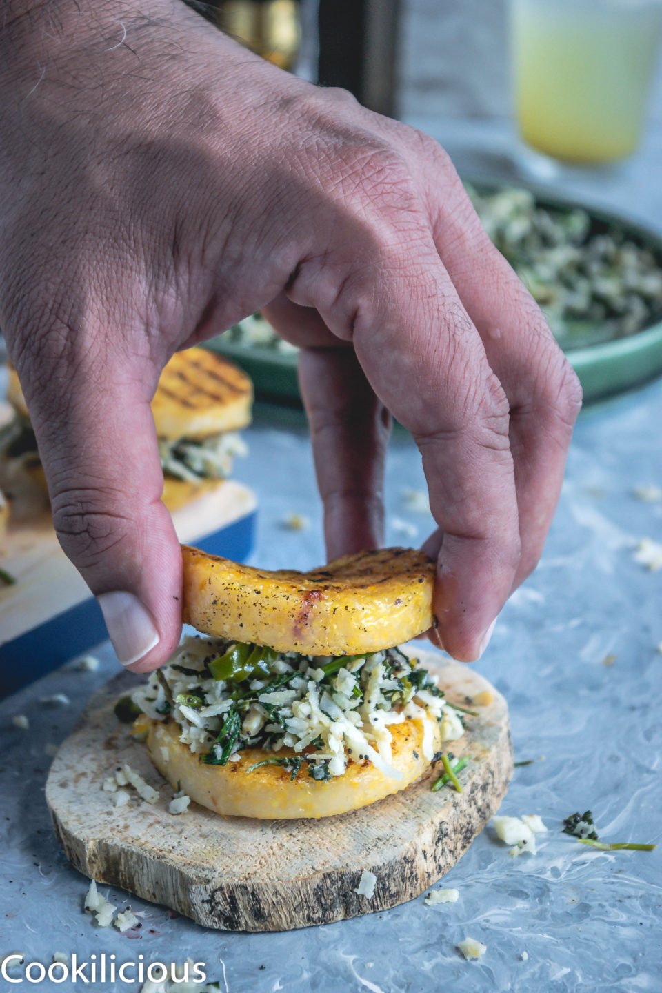a hand placing a grilled polenta over the prepared cilantro masala, like a sandwich makes a great vegan gluten free recipes