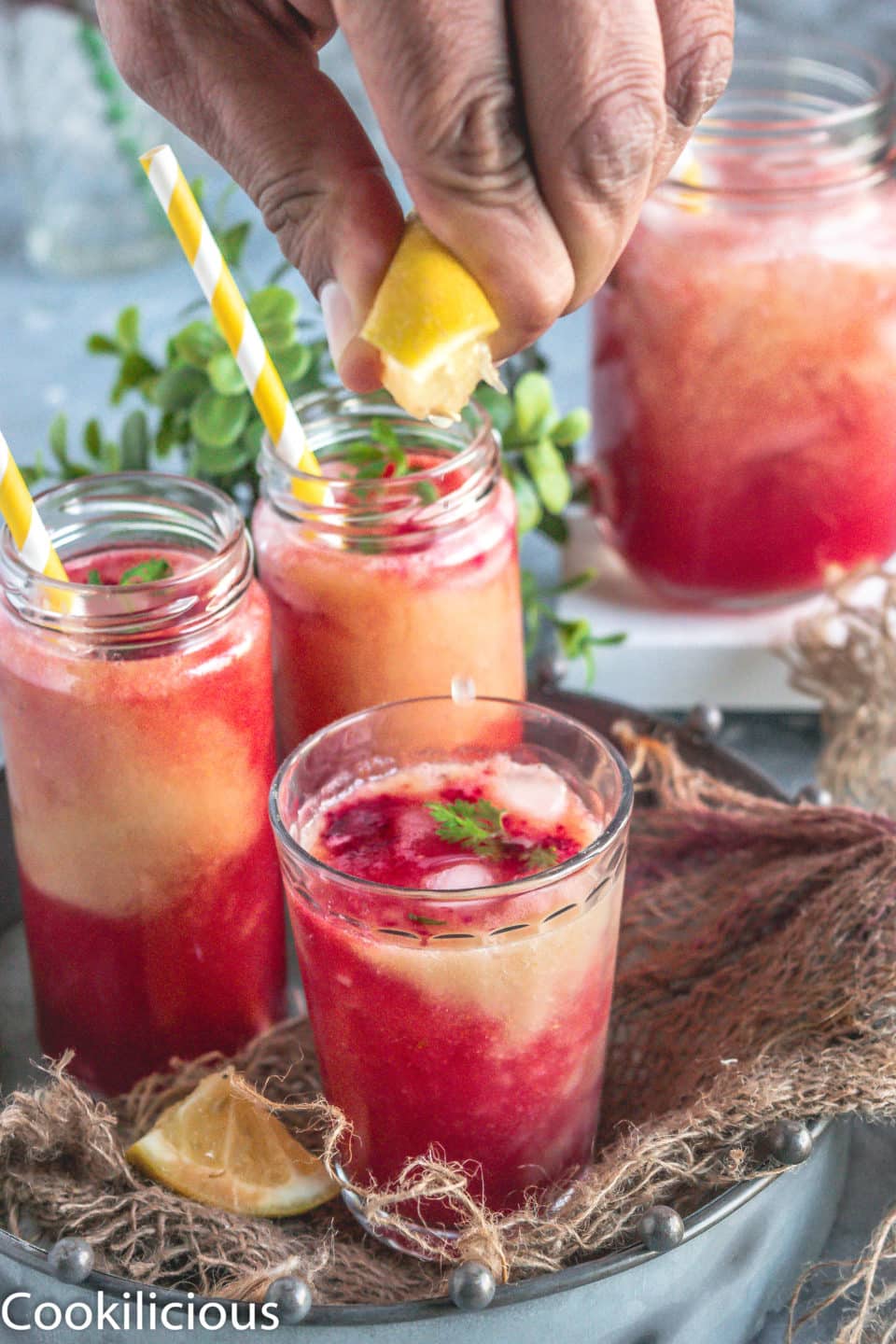 a hand squeezing lemon juice over a glass of Fresh Guava & Watermelon Non Boozy Summer Drink