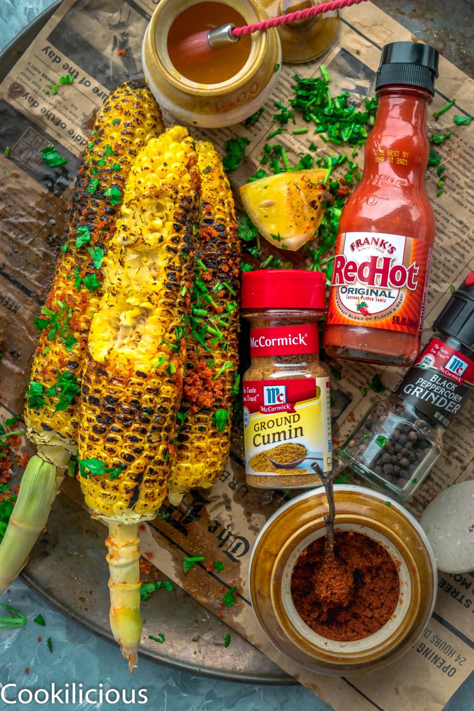 top angle shot of Indian Street Style Corn On The Cob with one of it half eaten and a lemon wedge on the side