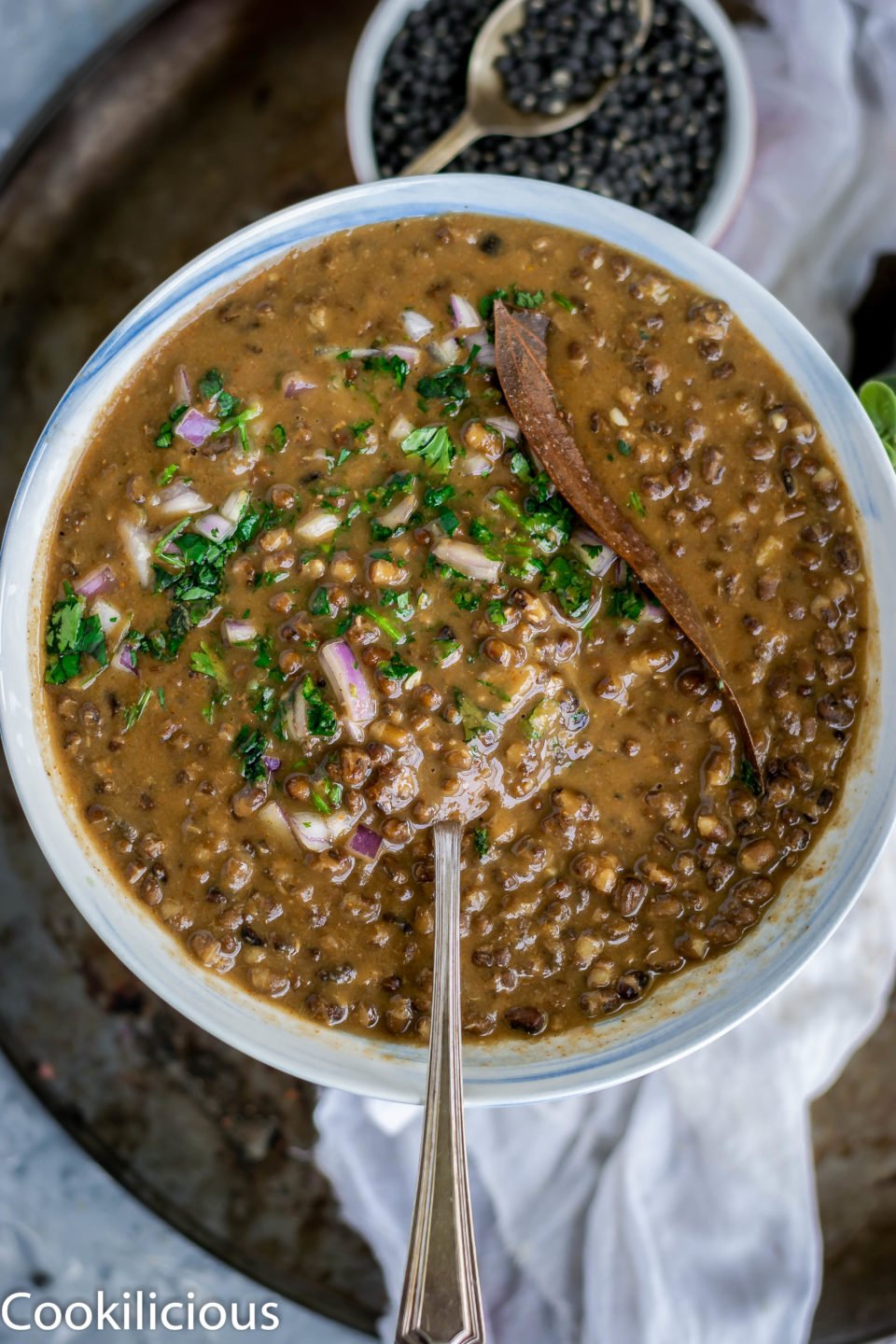 top angle shot of a bowl filled with Black Lentils Stew | Kali Dal | Maa Ki Daal and a spoon in it