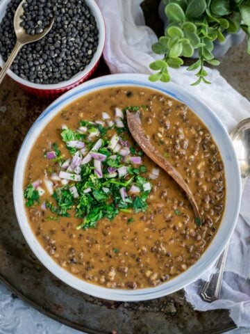 a bowl filled with Black Lentils Stew | Kali Dal | Maa Ki Daal and black lentils in a bowl on the side