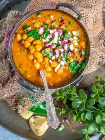 South Indian Chickpeas Curry | Chettinad Kondai Kadalai Kuzhambu in a kadai with a bunch of cilantro on the side