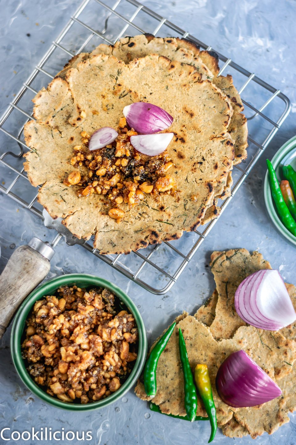 flatlay image of Dill Flavored Jowar Bhakri with thecha, onions and green chillies on the side