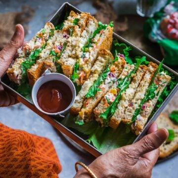 a set of hands holding a tray filled with Indian Style Spiced Yogurt Sandwiches