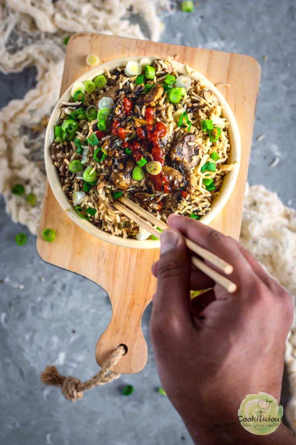 a hand holding chopsticks digging into a Japanese fried rice bowl