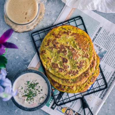 flat lay image of Lentil Pancakes with Leftover Dal with a bowl of yogurt dip and a coffee mug on the side