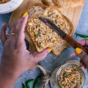 a set of hands spreading butter over a bread slice