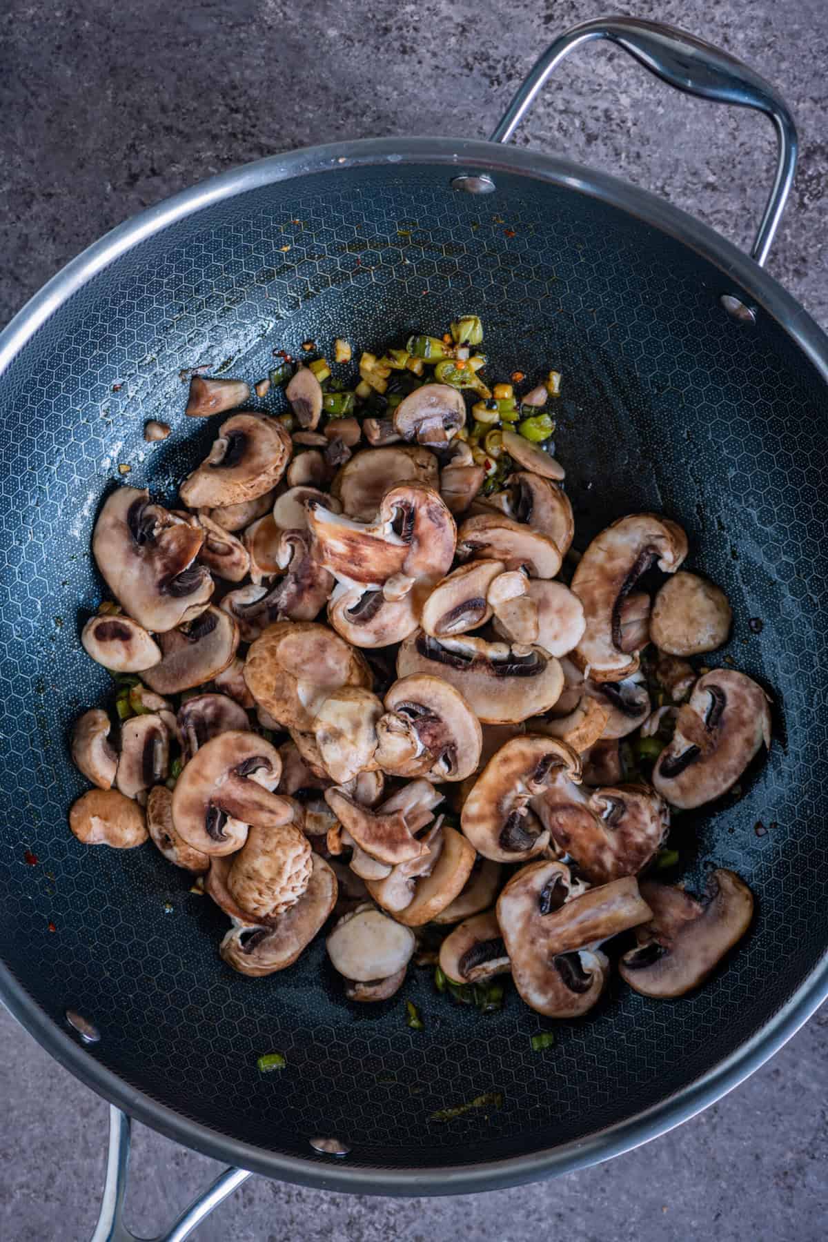 Sliced mushrooms caramelizing in a wok for homemade mushroom fried rice.
