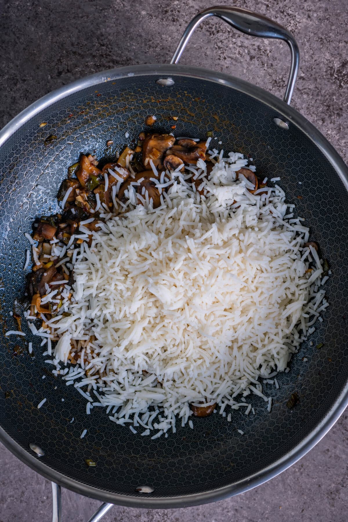 Cooked rice tossed with mushrooms in a wok to make quick vegan mushroom fried rice.