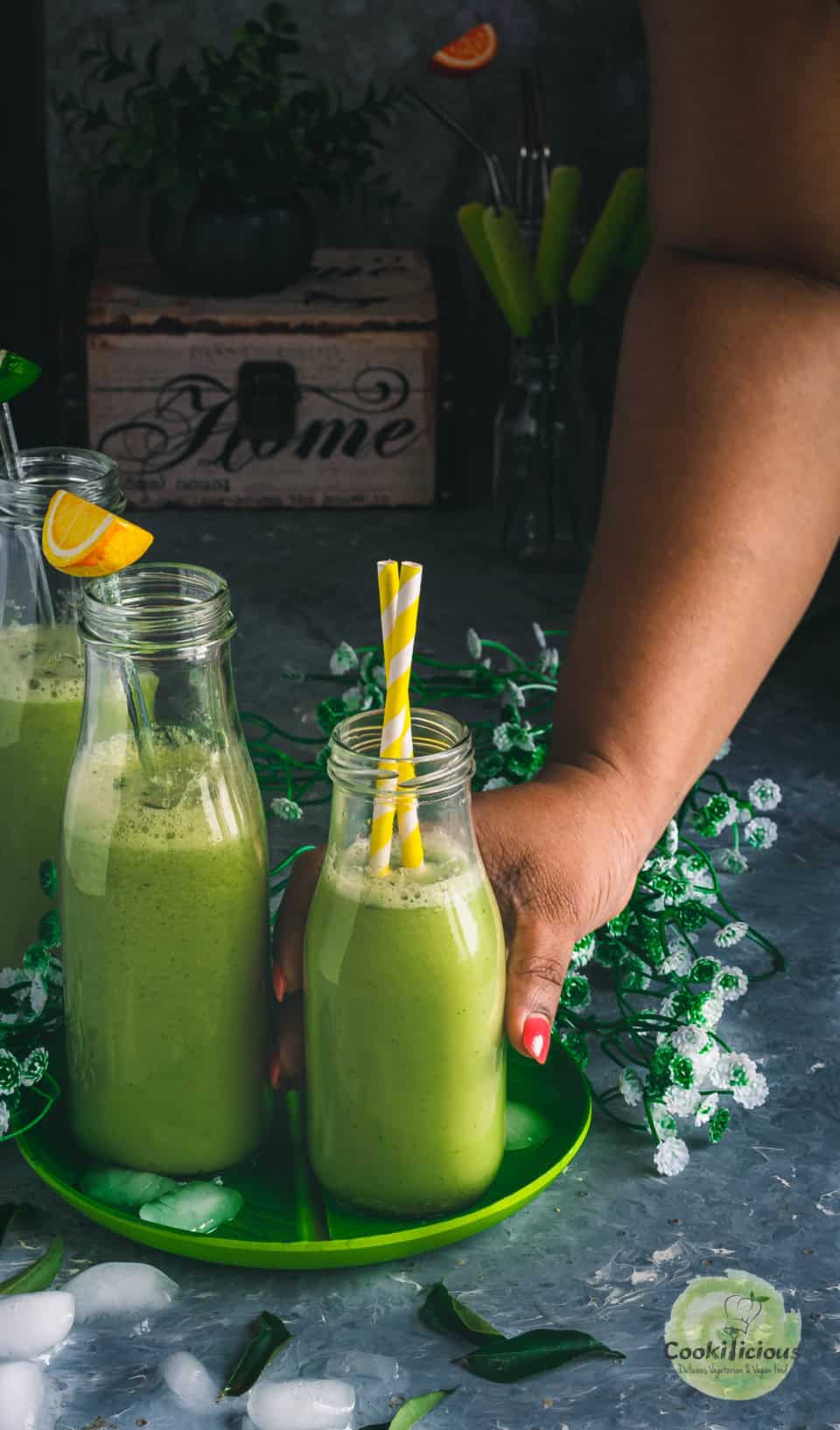 a hand reaching out to pick up a glass of cucumber chaas