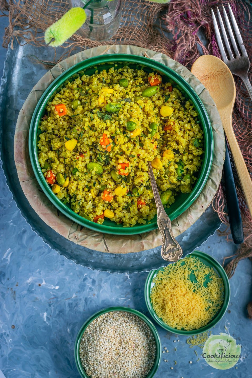 a bowl filled with Vegetable Quinoa Upma with a spoon in it and few spoons on the side