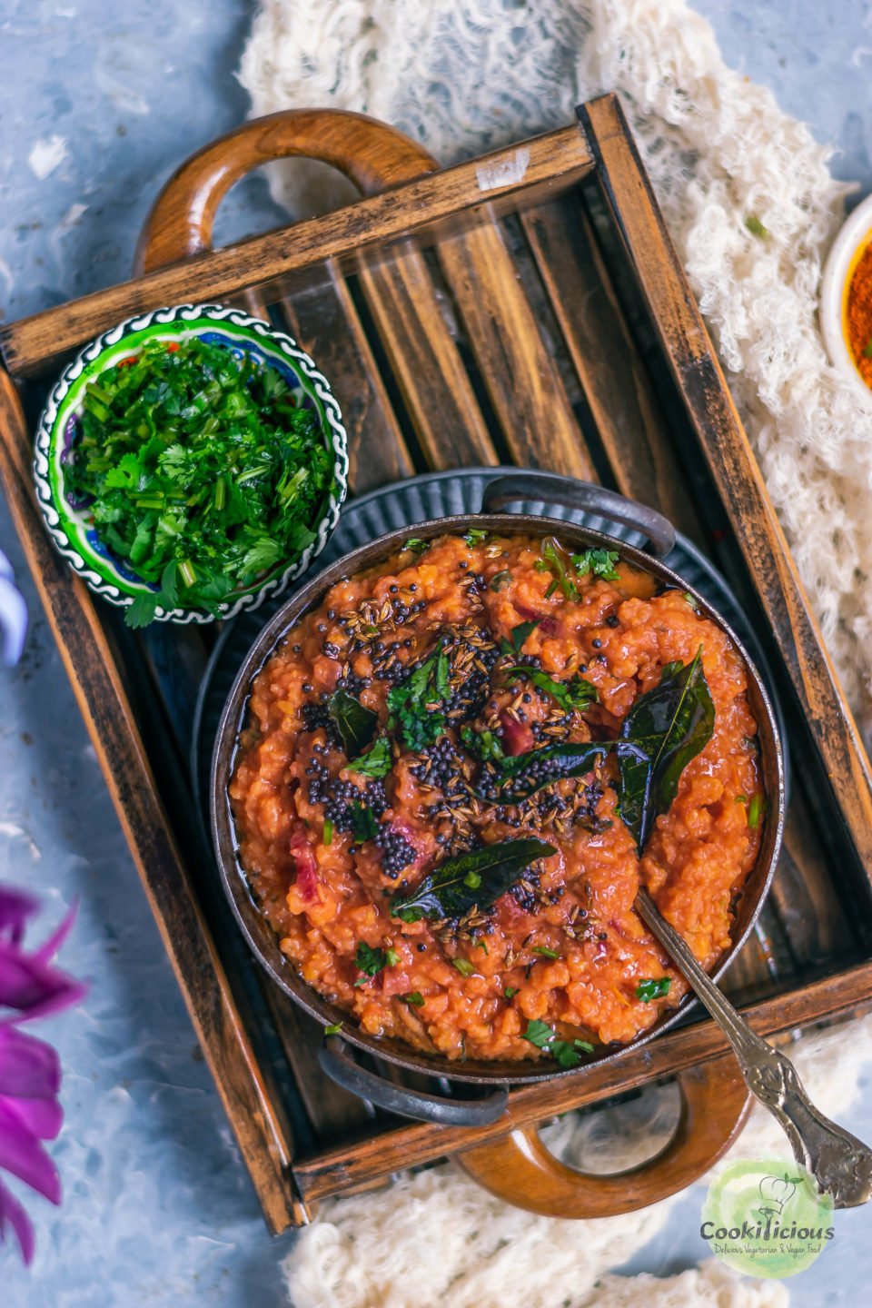 a bowl of rasam rice along with a bowl of dried cilantro placed in a tray