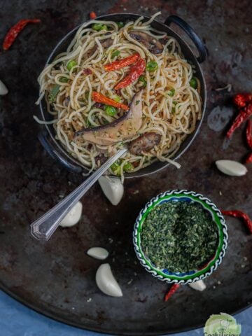 a bowl of Chilly Garlic Noodles next to a small bowl of parsley