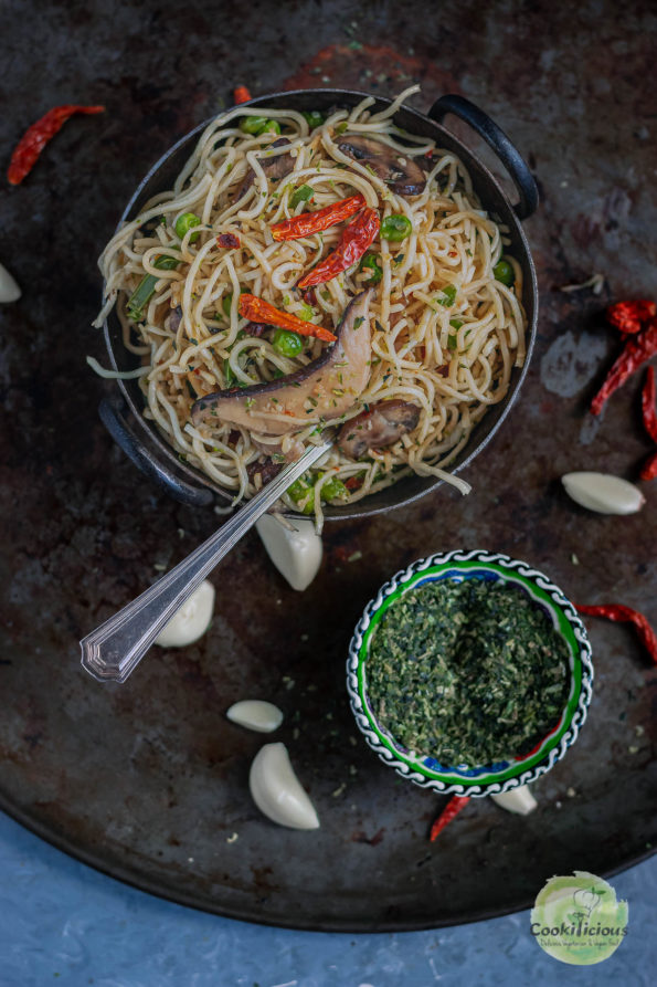 a bowl of Chilly Garlic Noodles next to a small bowl of parsley