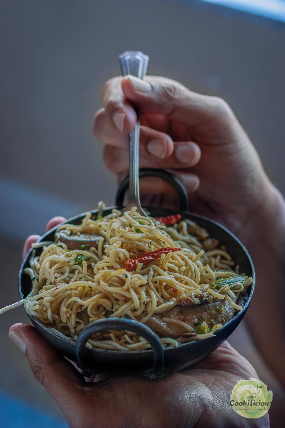 a set of hands enjoying a bowl of Chilly Garlic Noodles