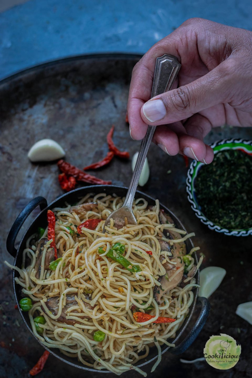 close up shot of a hand digging a fork into a bowl of Chilly Garlic Noodles