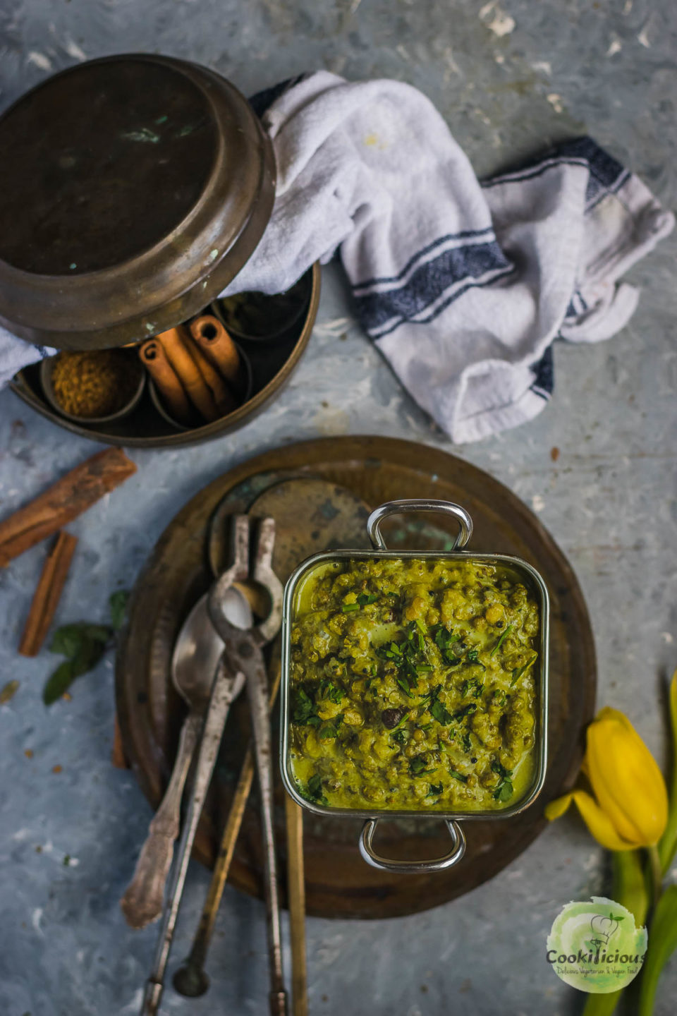 a square bowl filled with mung bean sprouts Coconut Indian vegan recipe and cutlery on the side and a kitchen towel on the top