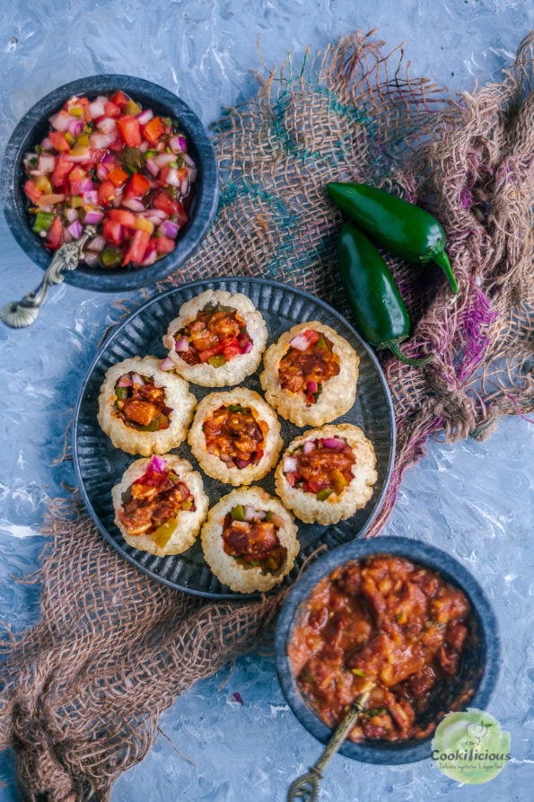 a plate full of Indian Mexican Pani Puri with a bowl of salsa on one side and a bowl of beans in tomato gravy on the other side