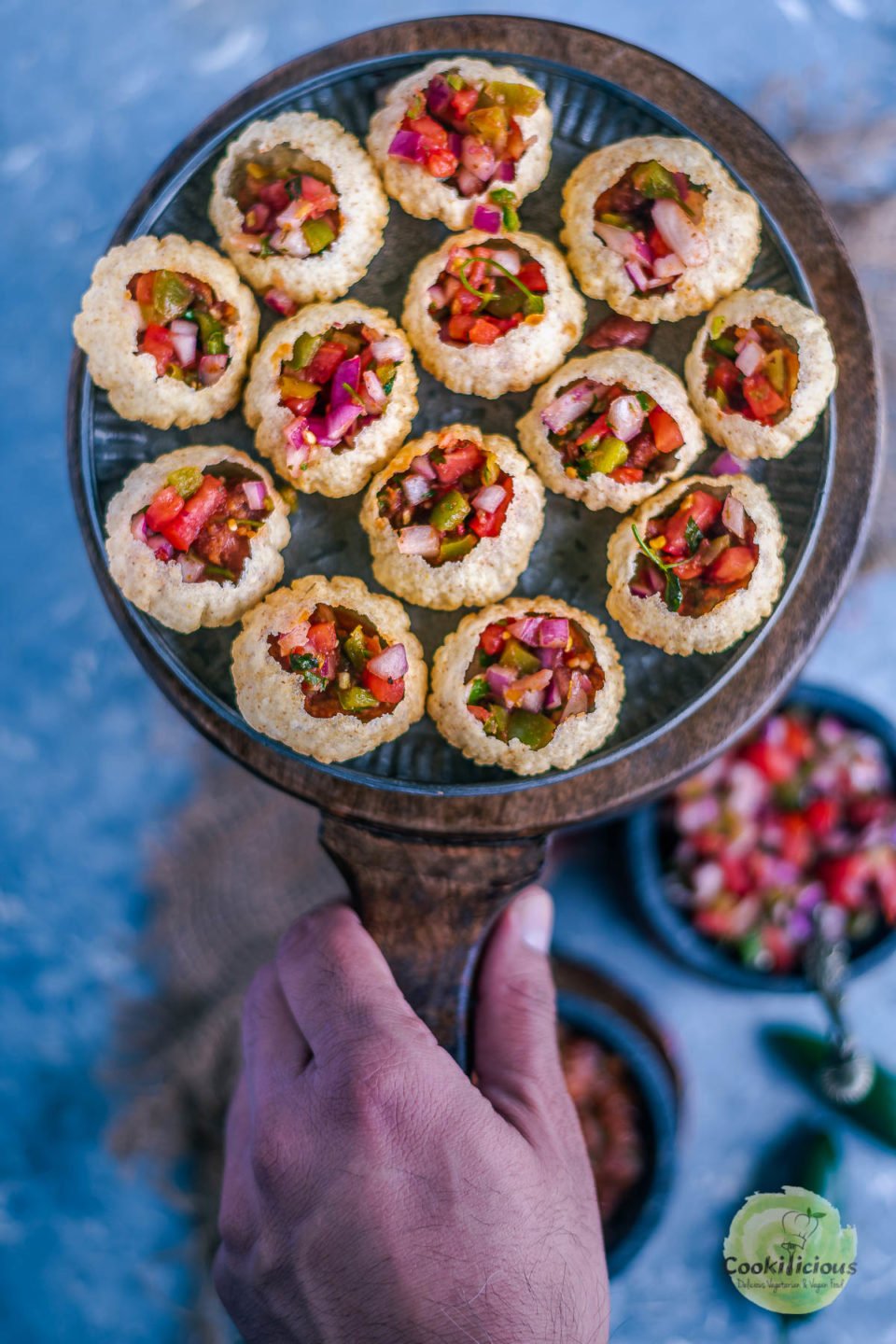 a hand holding a platter of Indian Mexican Pani Puri