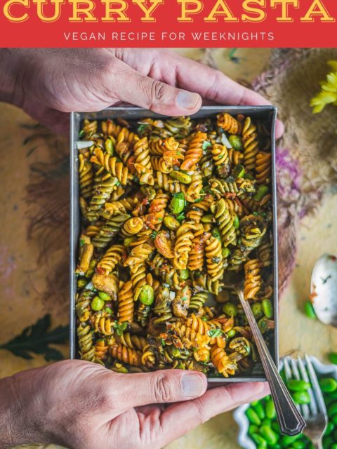 pair of hands holding the serving platter that's filled with Indian Pasta Recipe | One-Pot Vegan Curry Pasta Dish and text at the top