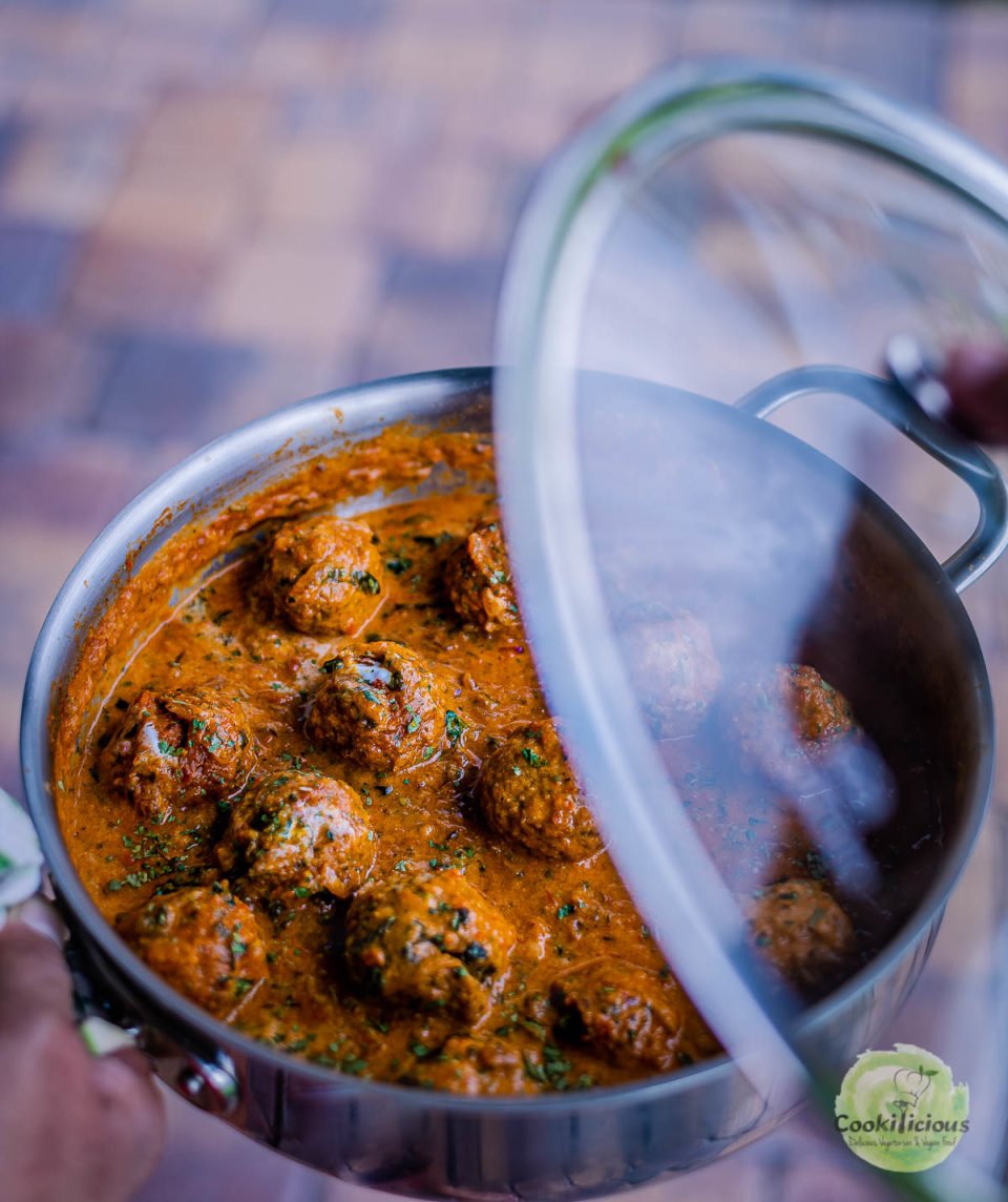 Spicy Kofta Curry with Plant-Based Meatballs  in a pan with a partially lifted lid 