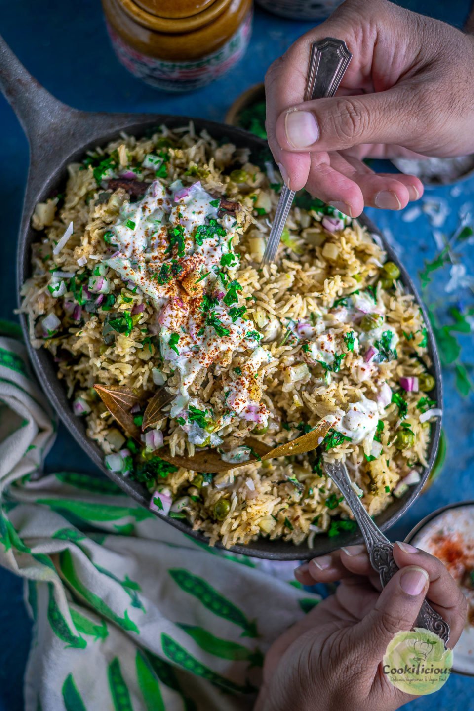 2 people digging into a platter of Potato Rice With Mint with spoons in their hands